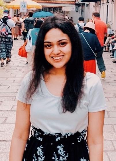 Ishira Parikh photo: A girl with black hair and brown eyes is dressed in black and white and smiling. 