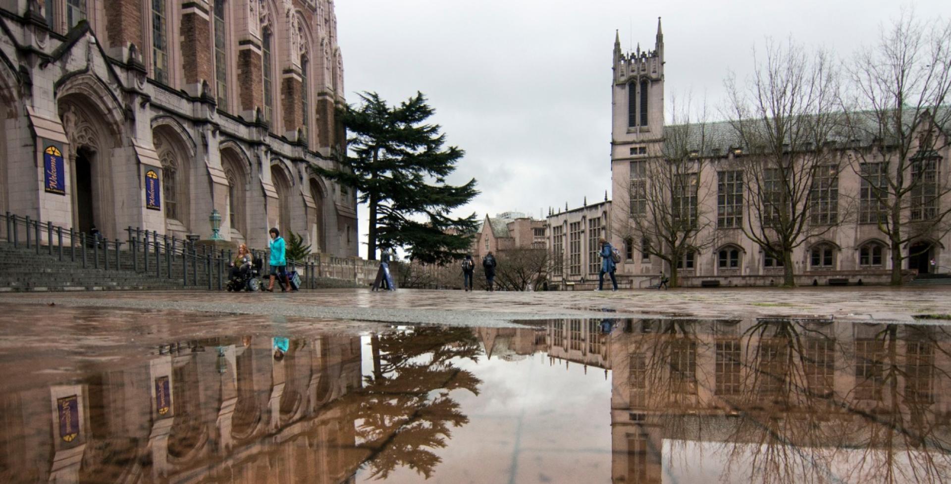 UW Red Square in the rain, a person using a wheelchair and a person walking past the library
